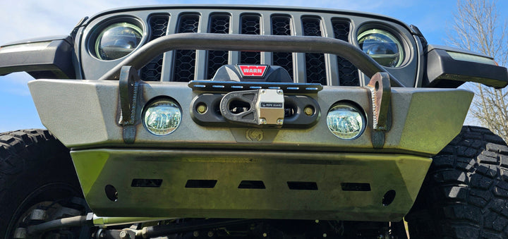 Close-up of a Jeep's front bumper with winch and fog lights.