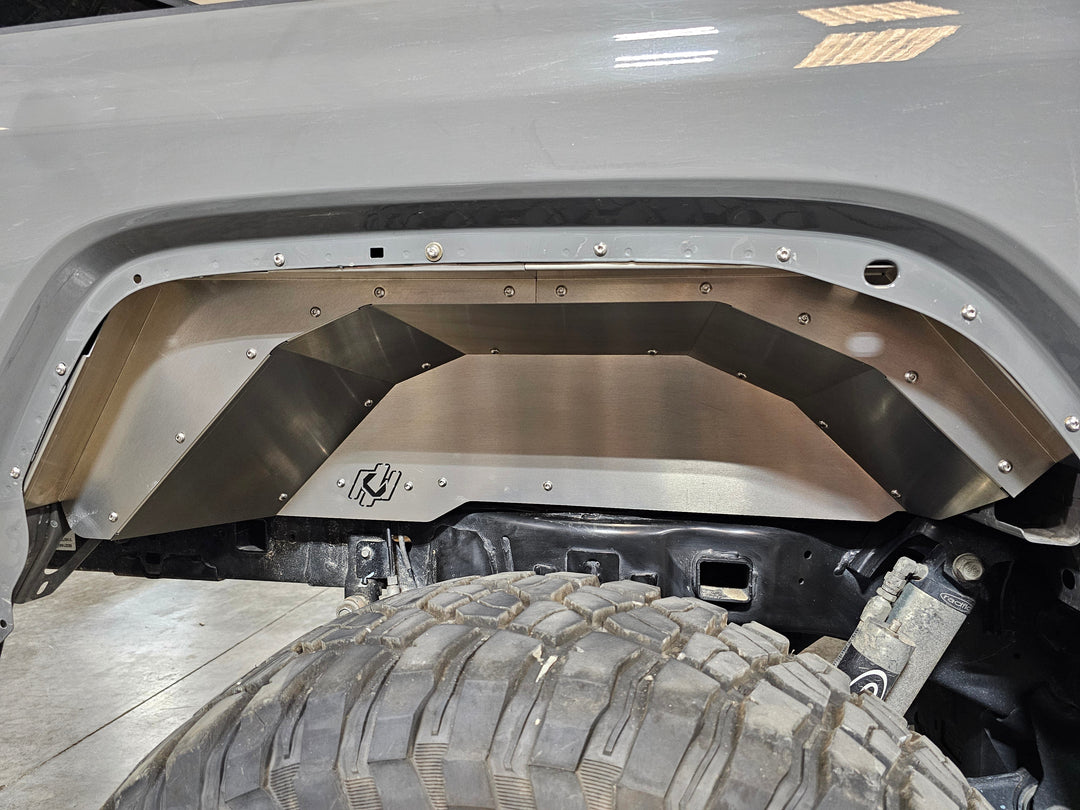 Metal wheel well liner installed in a vehicle.