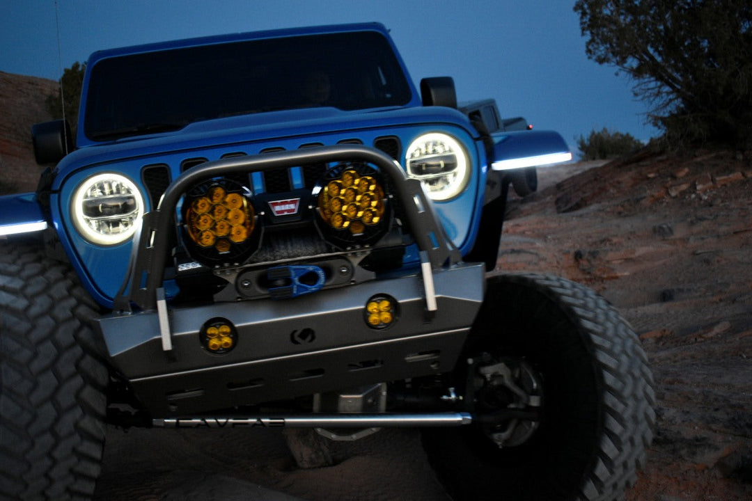 Best Jeep Wrangler build with aftermarket bumper and off-road lights tackling rocky terrain at dusk.