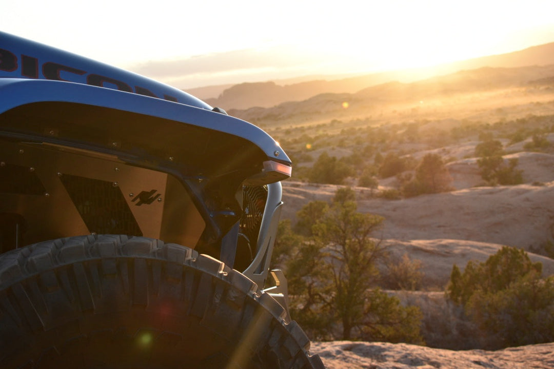 Modified Jeep front fender and oversized tire overlooking a desert sunset during a Jeep Sahara vs Rubicon off-road adventure