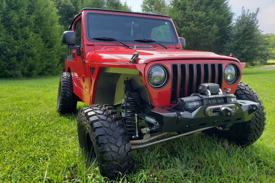 Red Jeep parked on grass as part of a discussion on does Jeep stand for Just Enough Essential Parts?