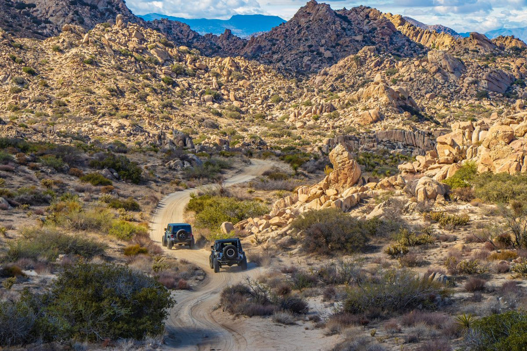 Two Jeeps on a mountain trail after using their Jeep owner’s manual to upgrade stock components for off-road use.